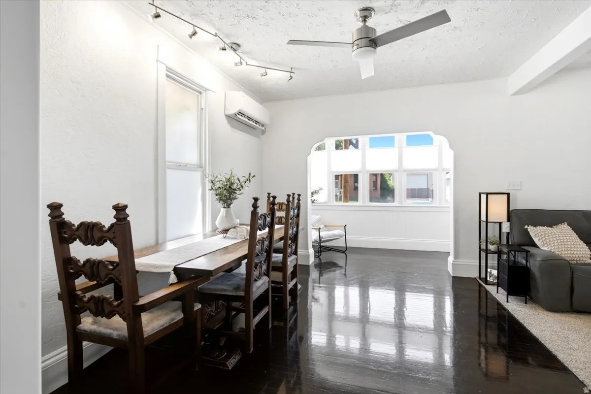 Open-concept living space featuring dark wood-finish ORIGINAL Hardwood flooring, white walls, and a decorative archway