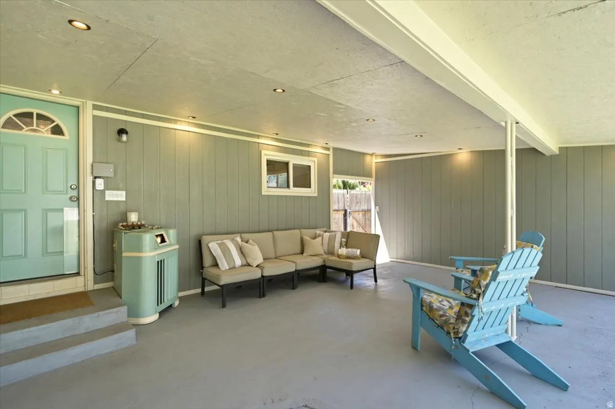 Covered outdoor living space featuring recessed lighting, a light blue door with an arched transom, durable board-and-batten siding, and a concrete patio.  HOT TUB, SOUNDS SYSTEM AND TV INCLUDED with full price offer!