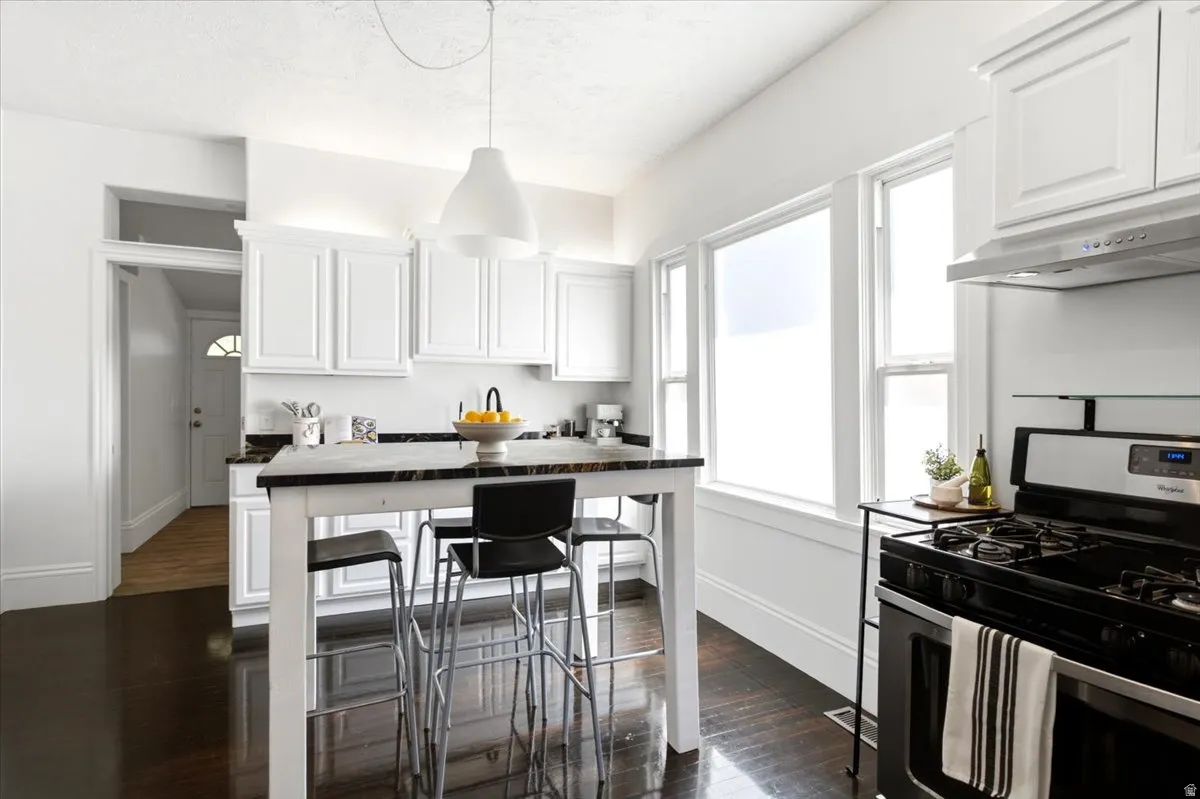 Kitchen featuring Original Hardwood -finish flooring, white cabinetry, and a black countertop island