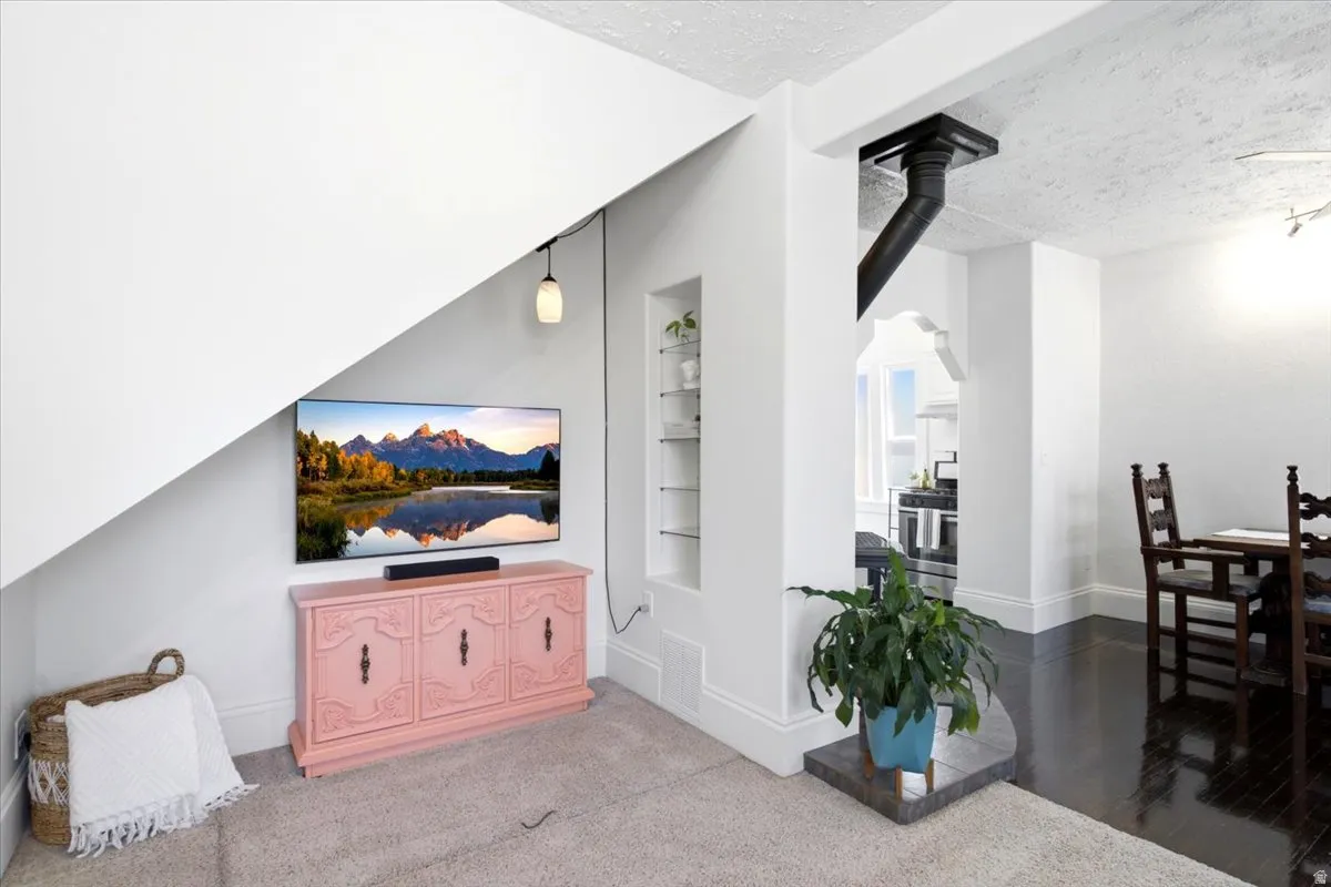 Open-concept living space featuring an angled wall, built-in shelving, dark Original hardwood- flooring, and a structural element with a black pipe