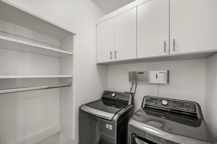 Laundry area featuring white cabinetry, integrated shelving, and a hanging rod