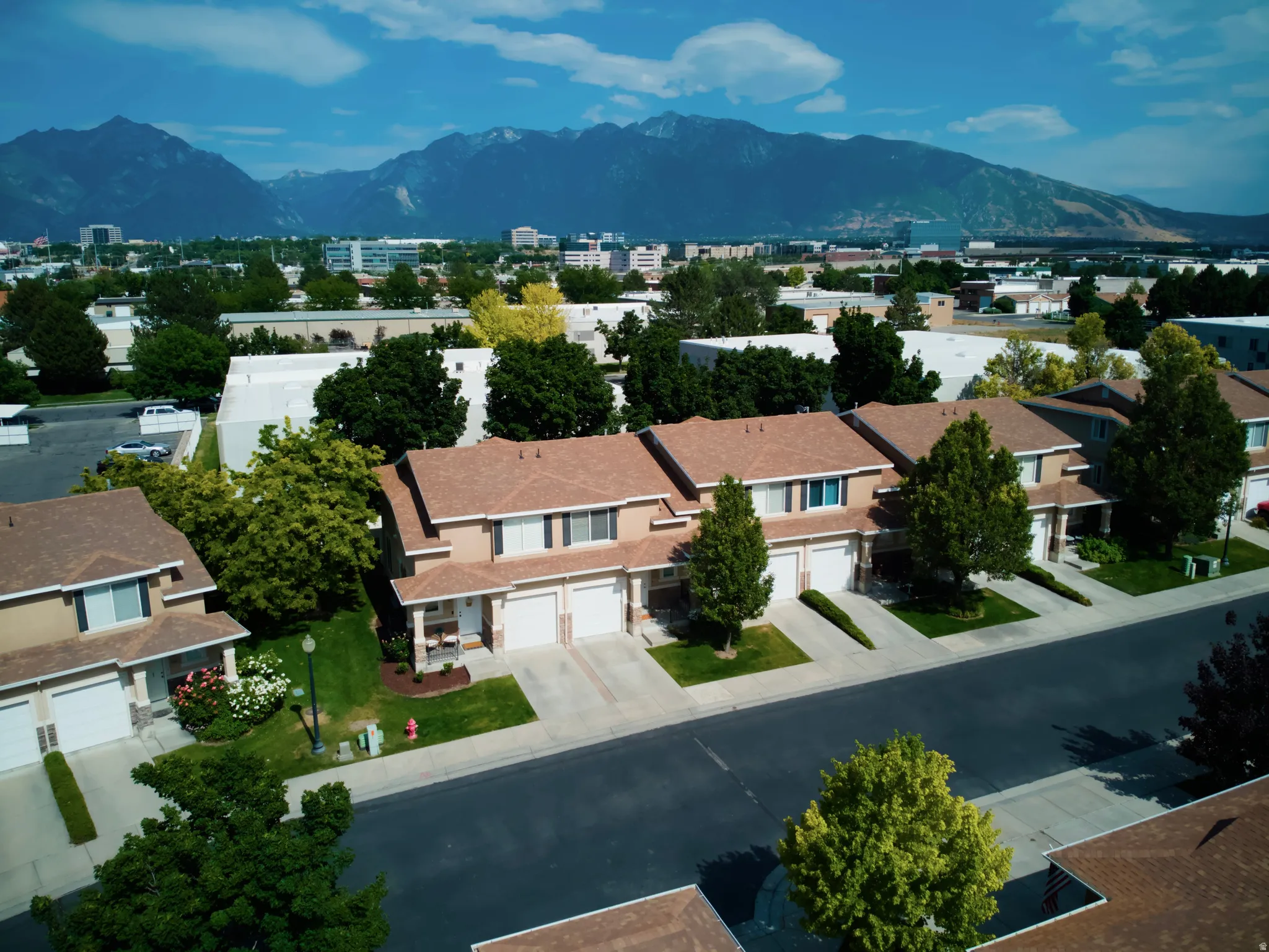 Residential street featuring townhomes with tan facades and attached garages