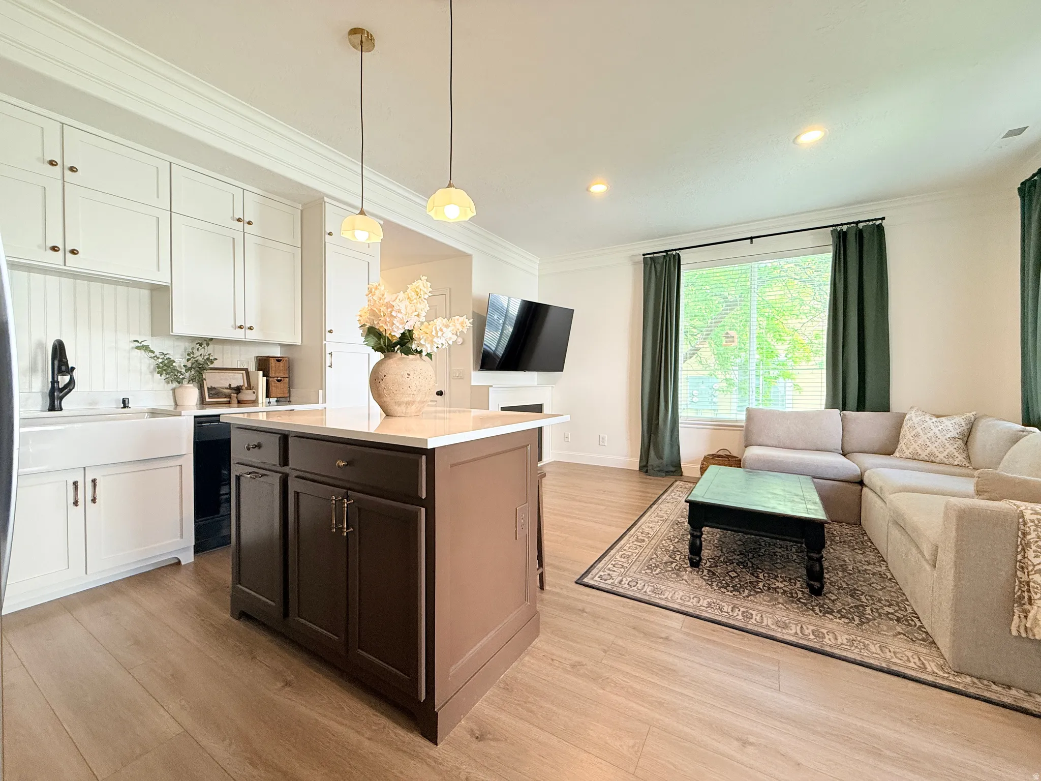 Open-concept living space featuring wood-finish flooring, recessed lighting, and a kitchen island with storage