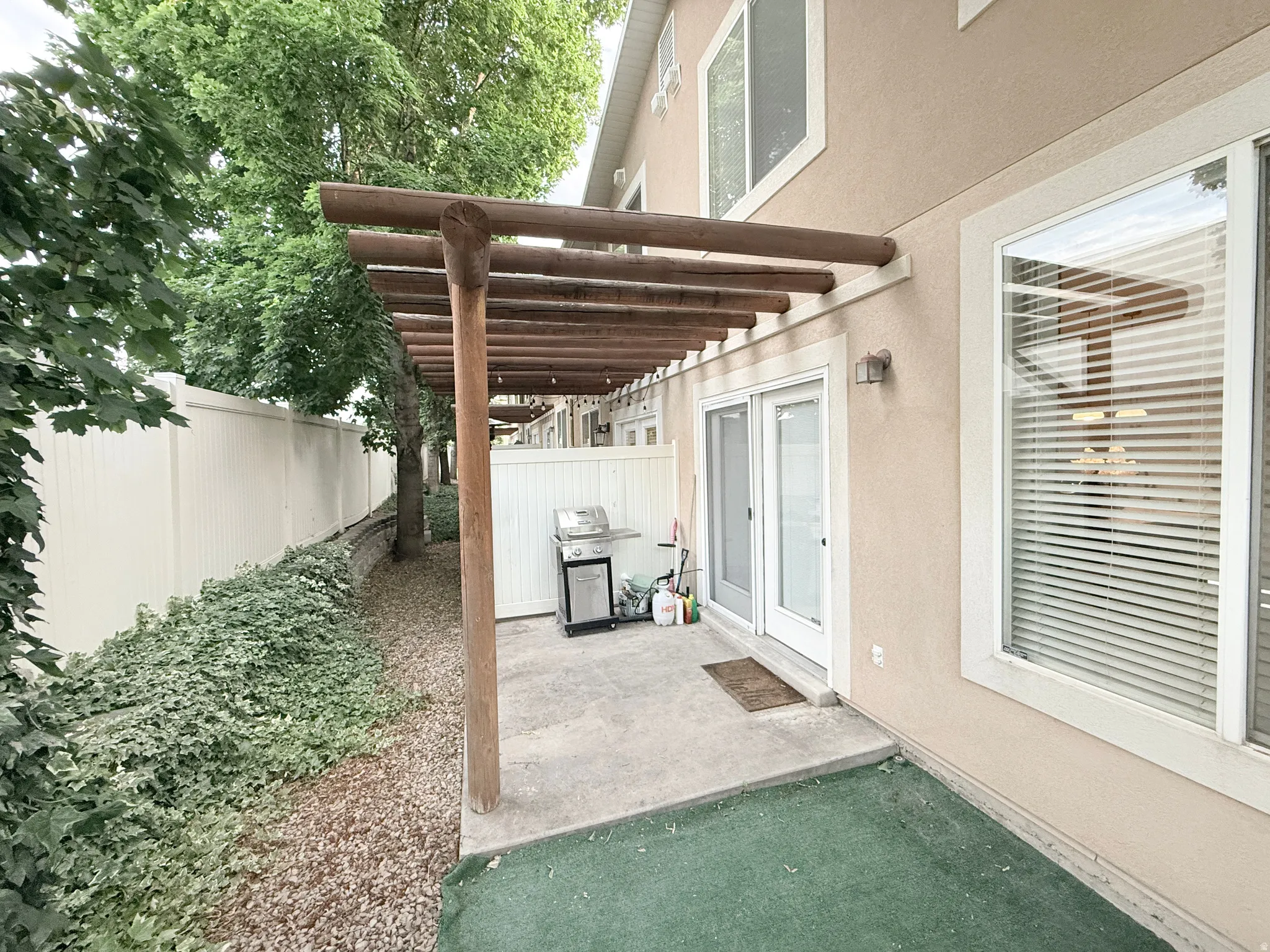 Private patio featuring a pergola, concrete slab, and artificial turf