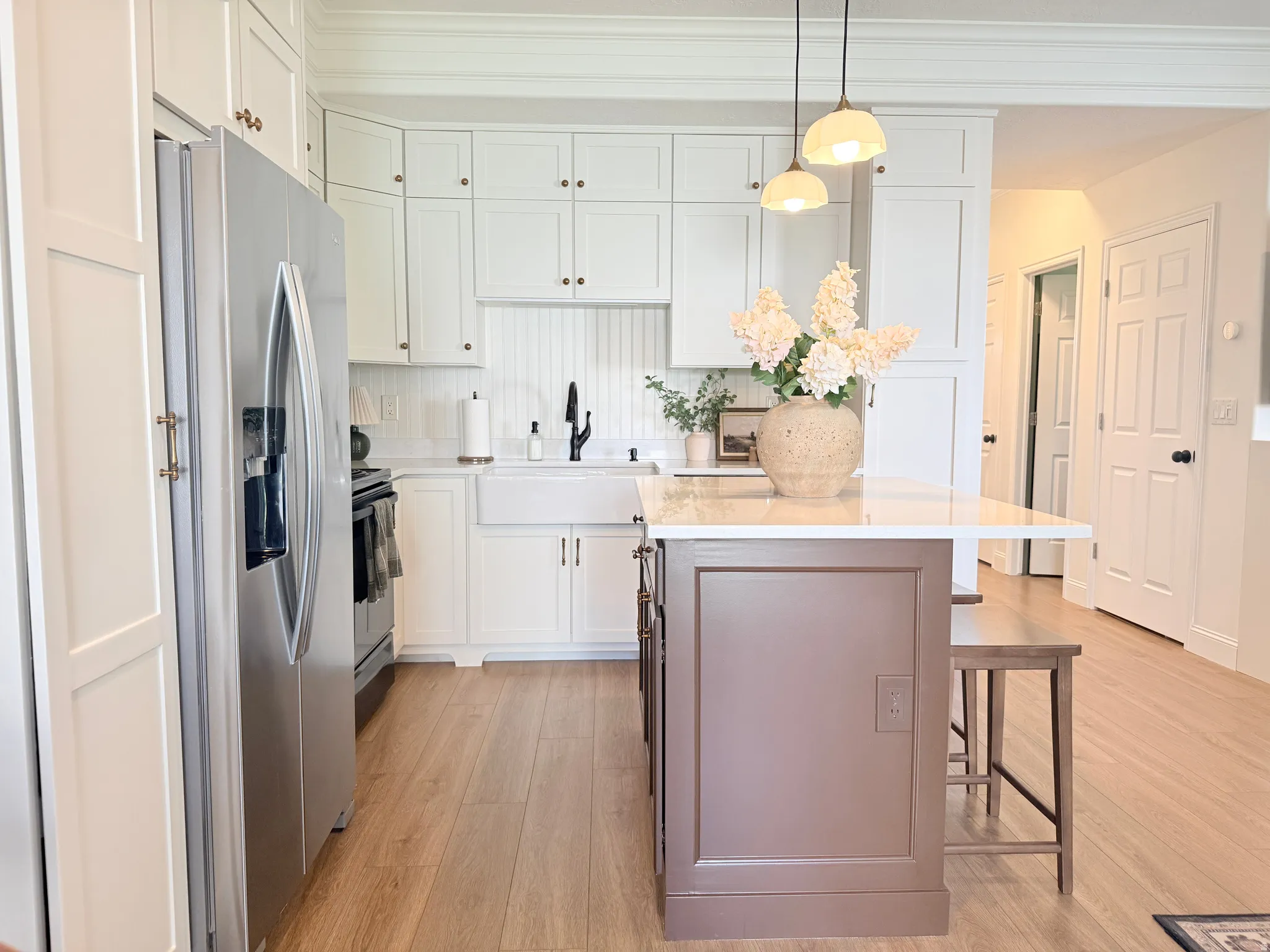 Gourmet kitchen featuring white shaker cabinetry, stainless steel appliances, a farmhouse sink, and a contrasting island with a white countertop