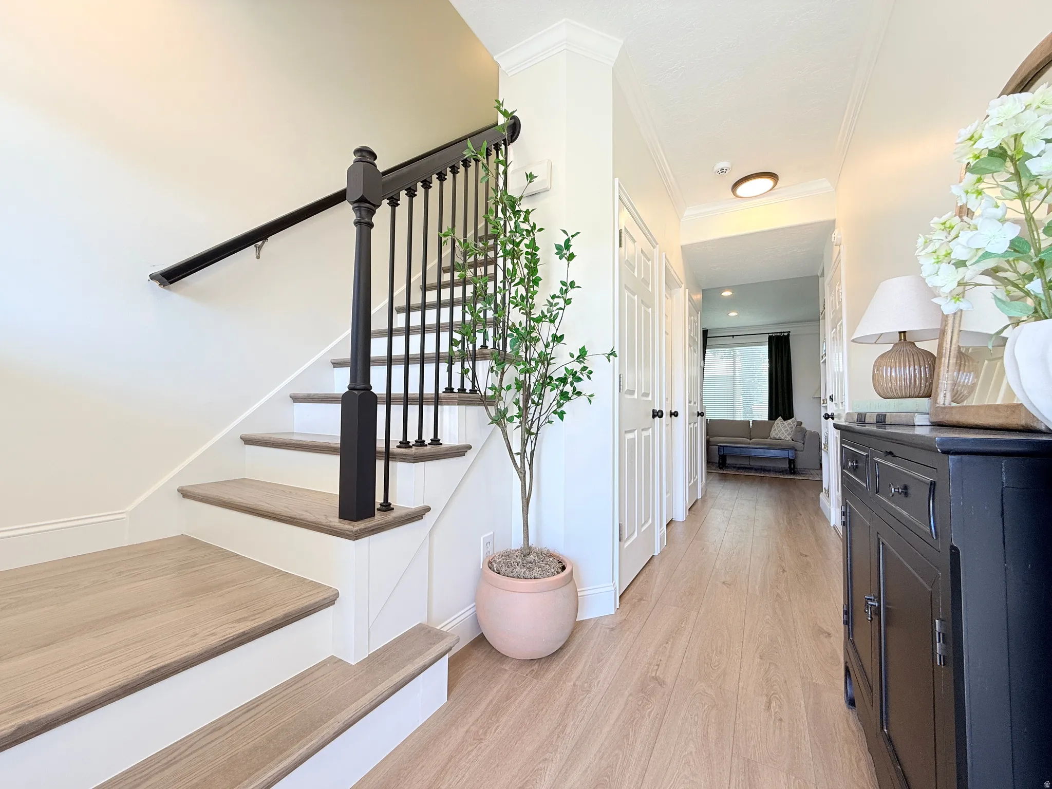 Staircase featuring wood-finish treads, white risers, and a black baluster and handrail system