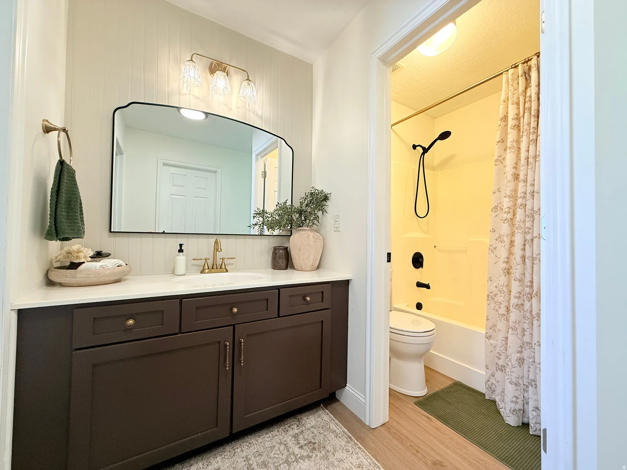 Bathroom featuring a dark wood-finish vanity with a white countertop and brass-finish fixtures