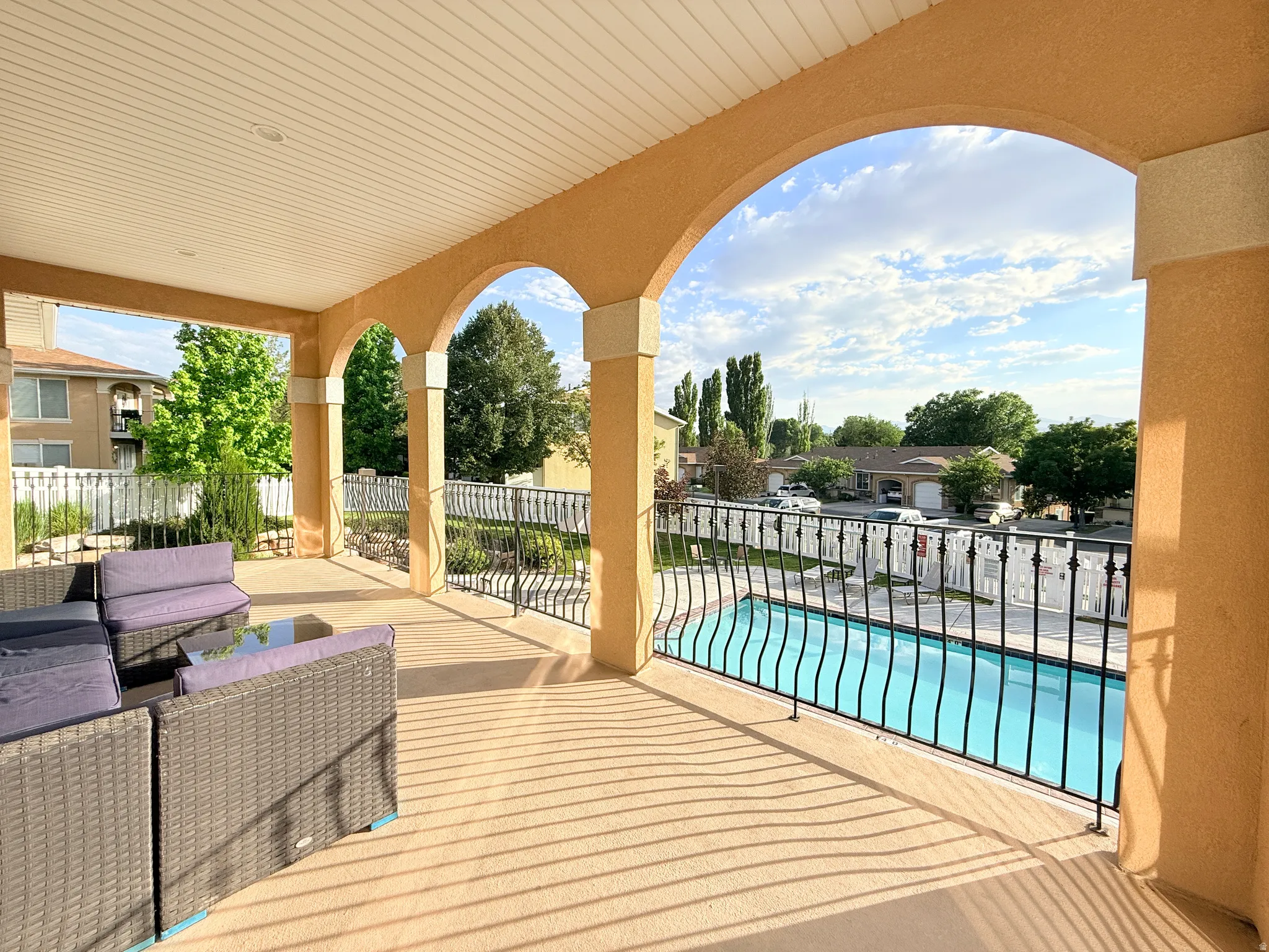 Covered balcony featuring arched openings, a textured stucco finish, and a slatted ceiling