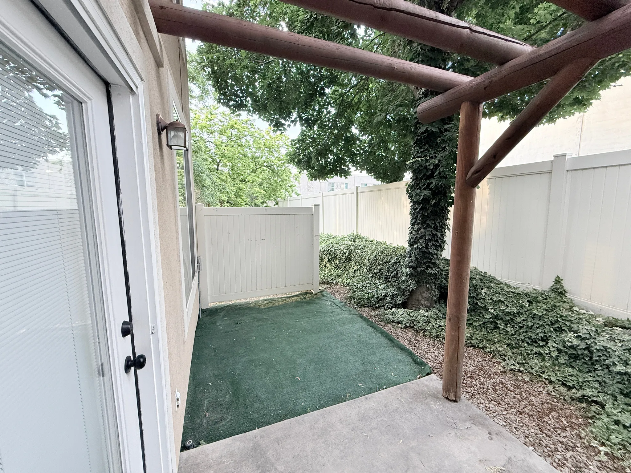 Private patio space featuring a concrete slab and artificial turf area
