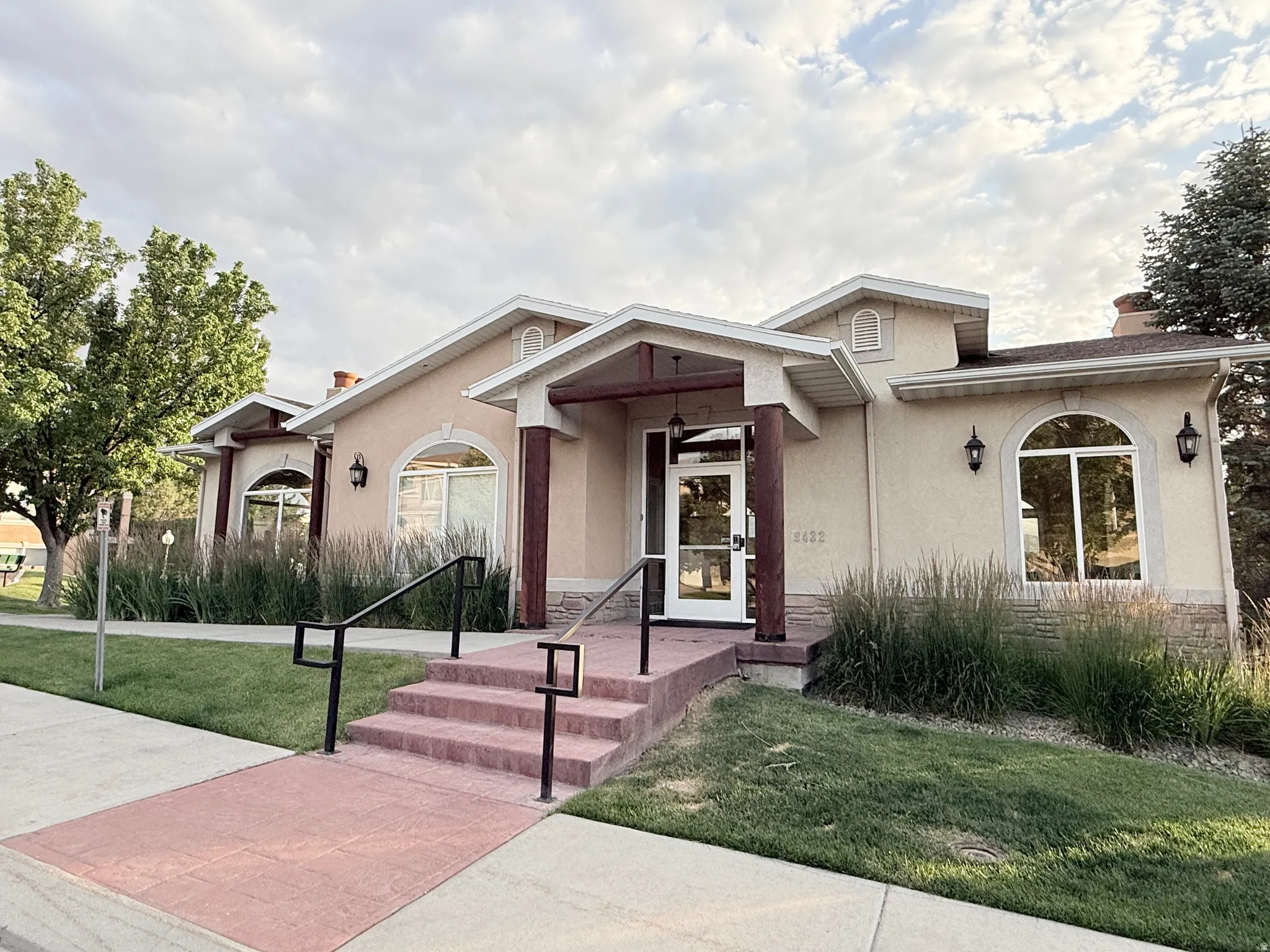 Stucco exterior with a covered entry, arched windows, decorative sconces, and a stone-clad foundation