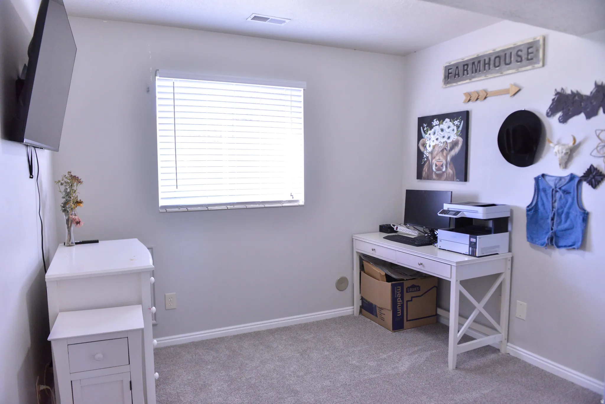 Light gray walls with white baseboards frame a window featuring white blinds