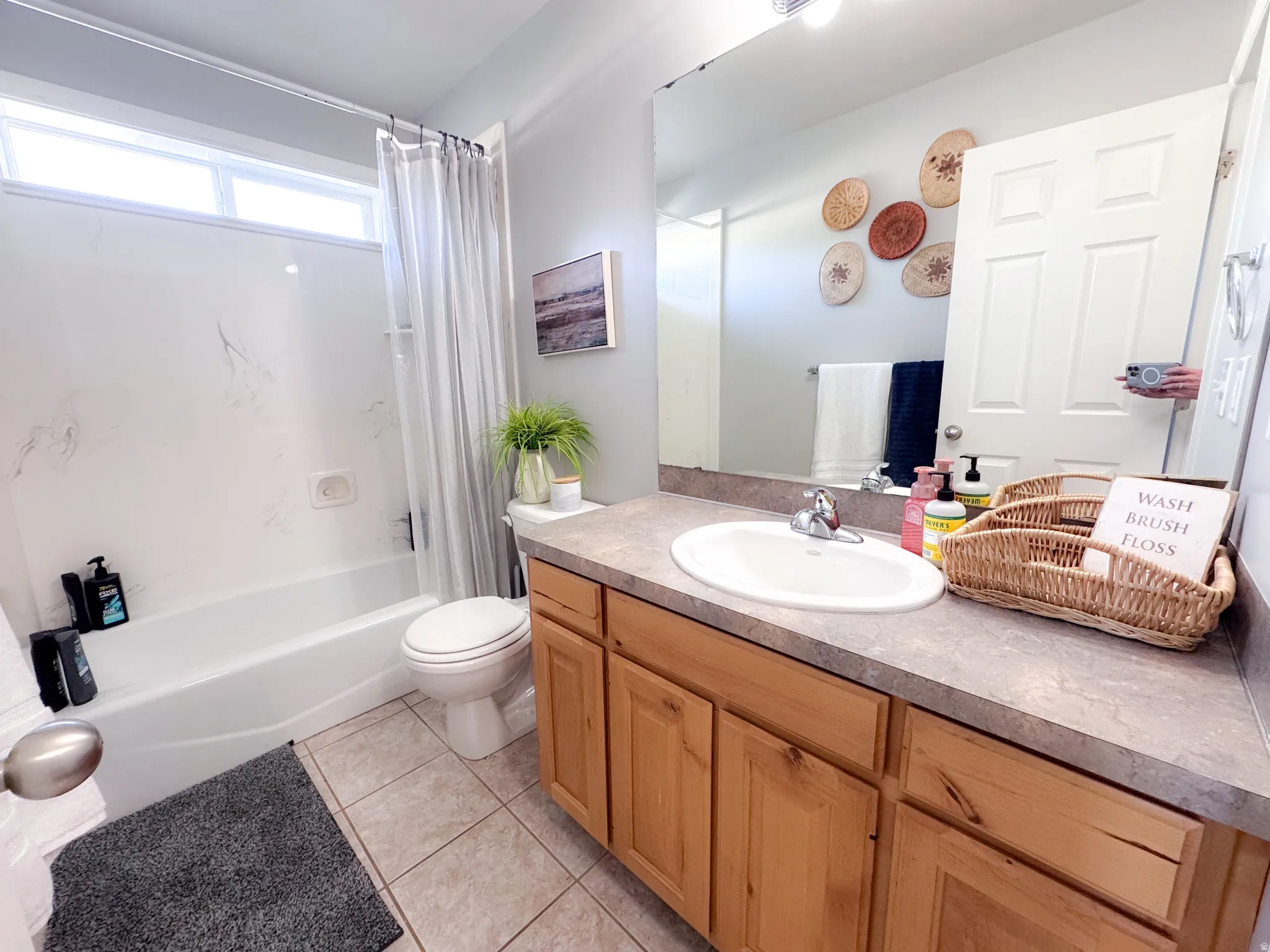 Bathroom featuring a full vanity with wood-finish cabinetry, an integrated sink, and a large mirror