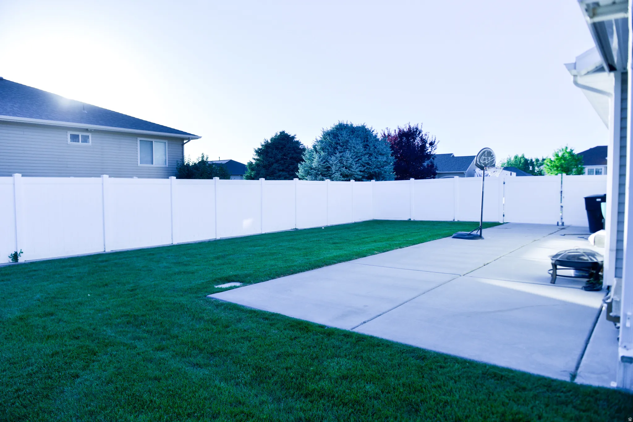 Expansive backyard featuring a large concrete patio and a manicured lawn
