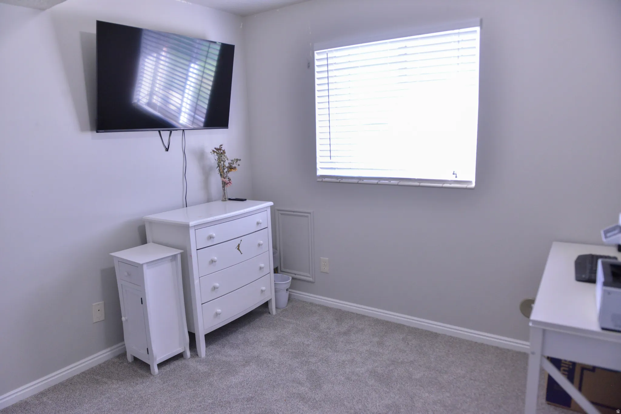 Carpeted room featuring a single window with horizontal blinds, light grey walls, and white baseboards
