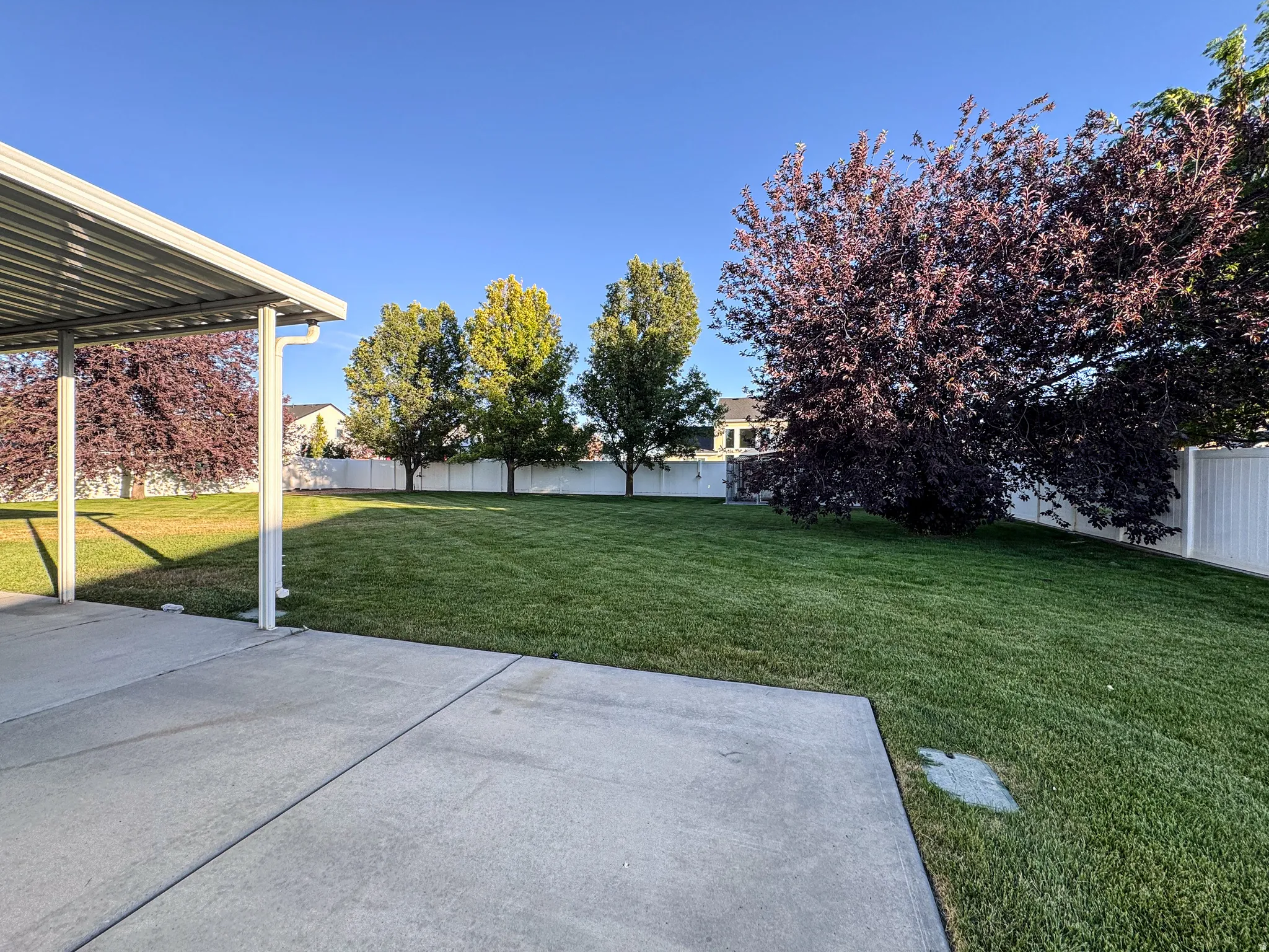 Expansive concrete patio with a covered section extending to a vast green lawn