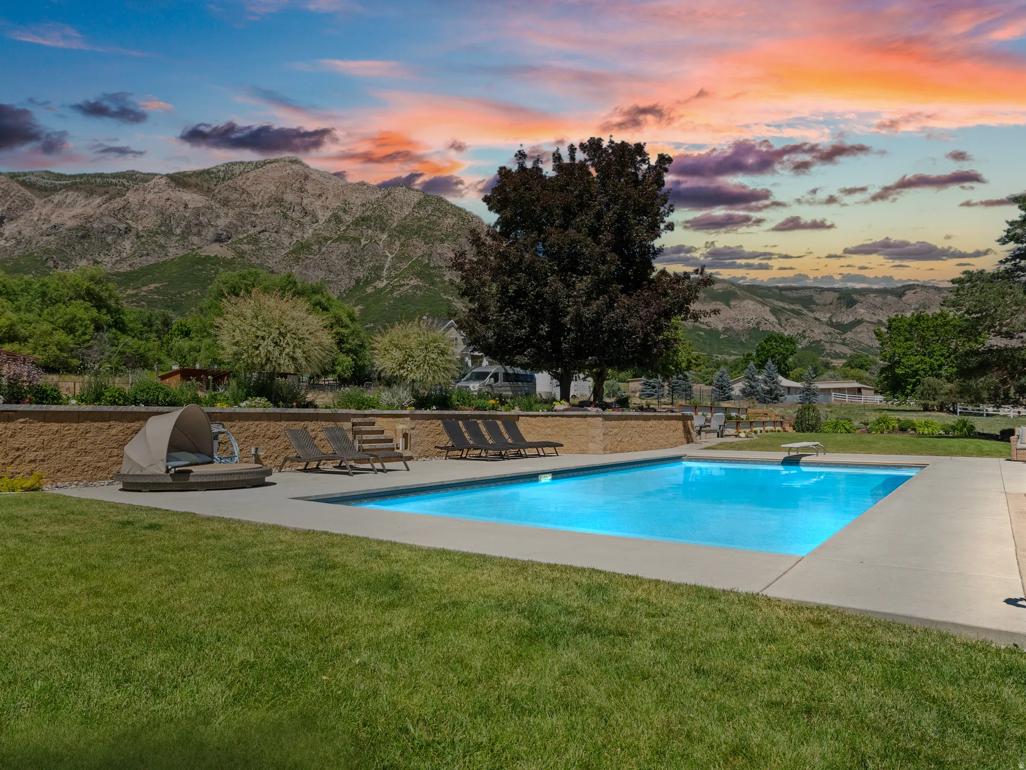 Rectangular inground swimming pool with a diving board, surrounded by a concrete patio and manicured lawn