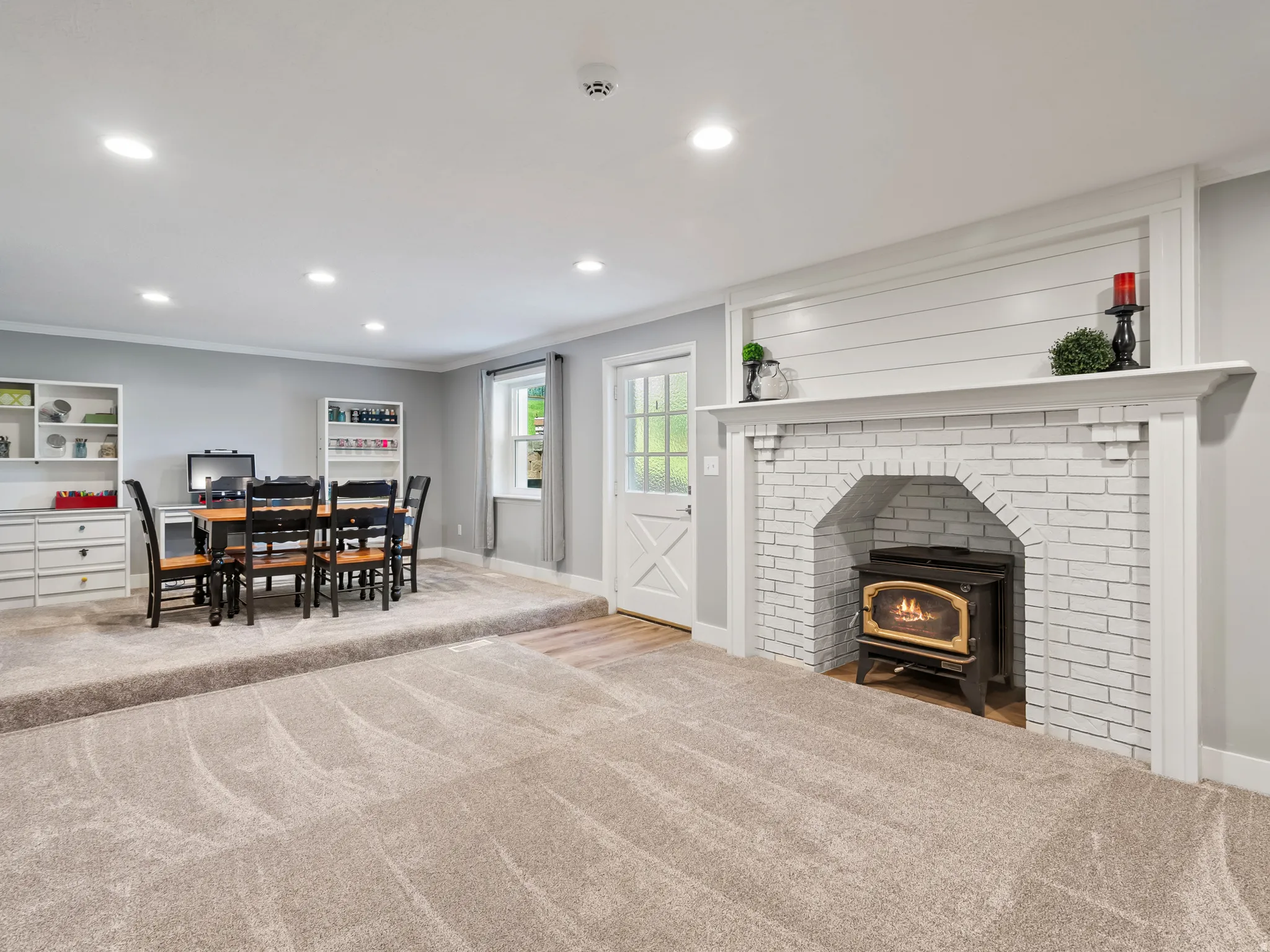 Living area featuring a white brick fireplace with a wood-burning insert and a shiplap accent wall