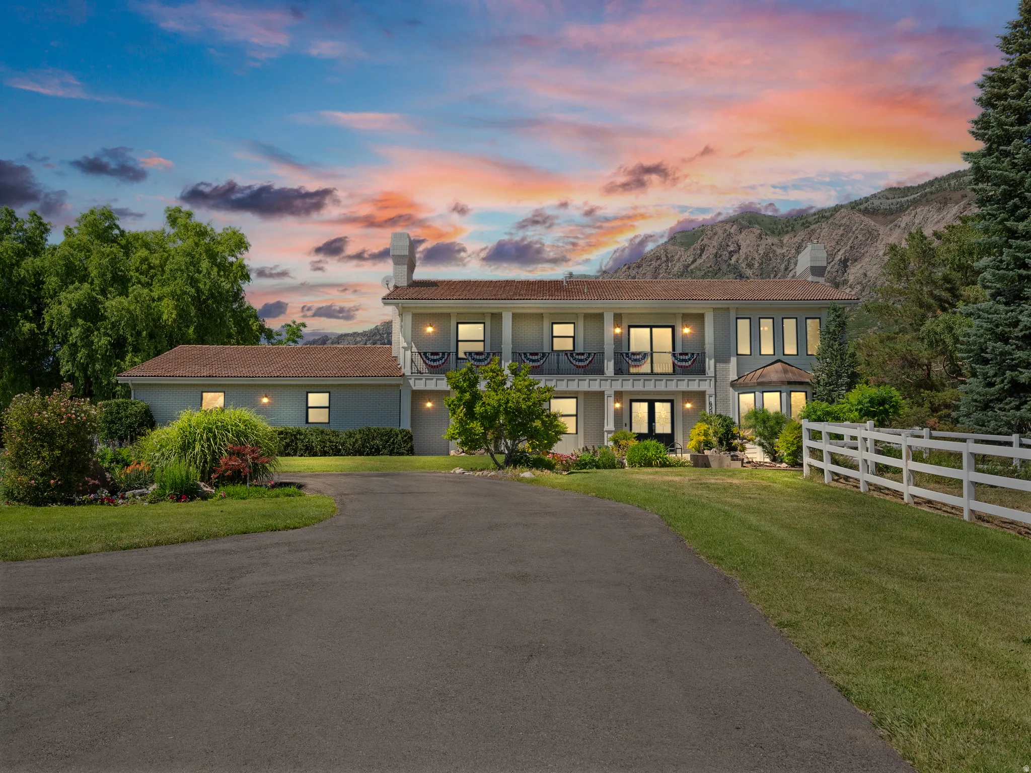 Two-story residence featuring a paved driveway, multiple windows, and a second-story balcony