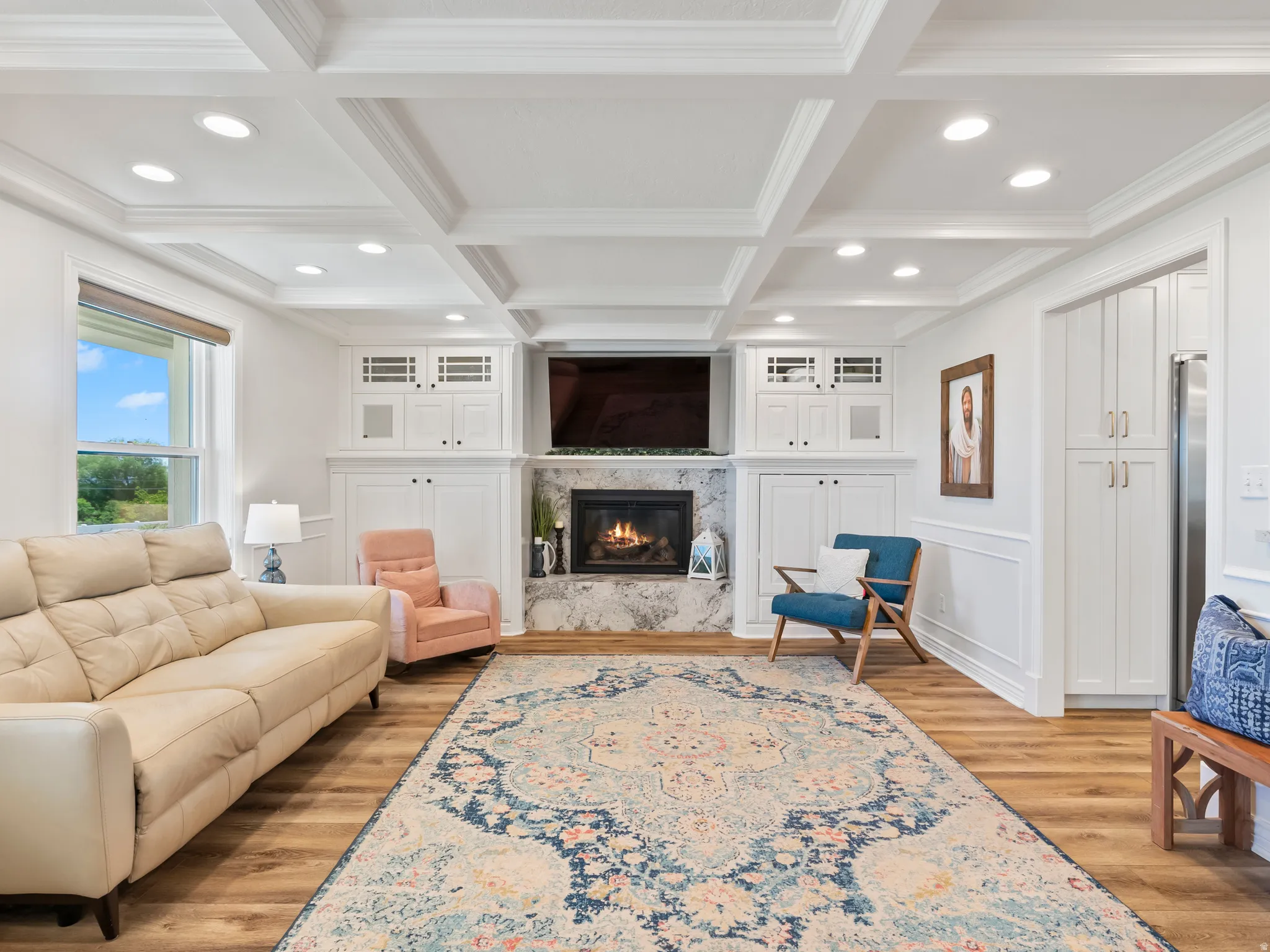 Living area featuring wood-finish flooring, a coffered ceiling with recessed lighting, and a fireplace with a stone surround