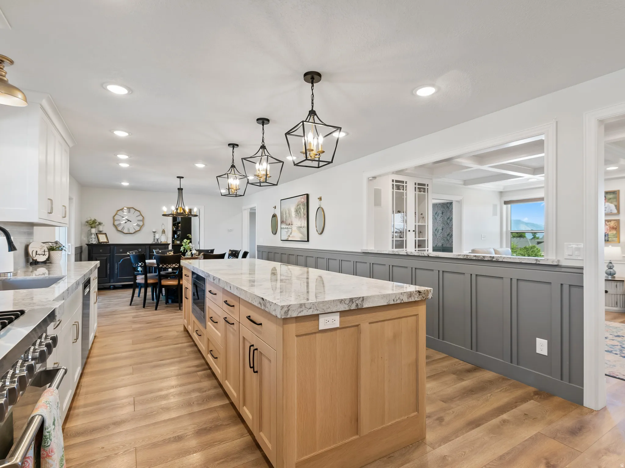 Spacious kitchen featuring a large light wood-finish island with integrated microwave, granite countertops, and recessed lighting