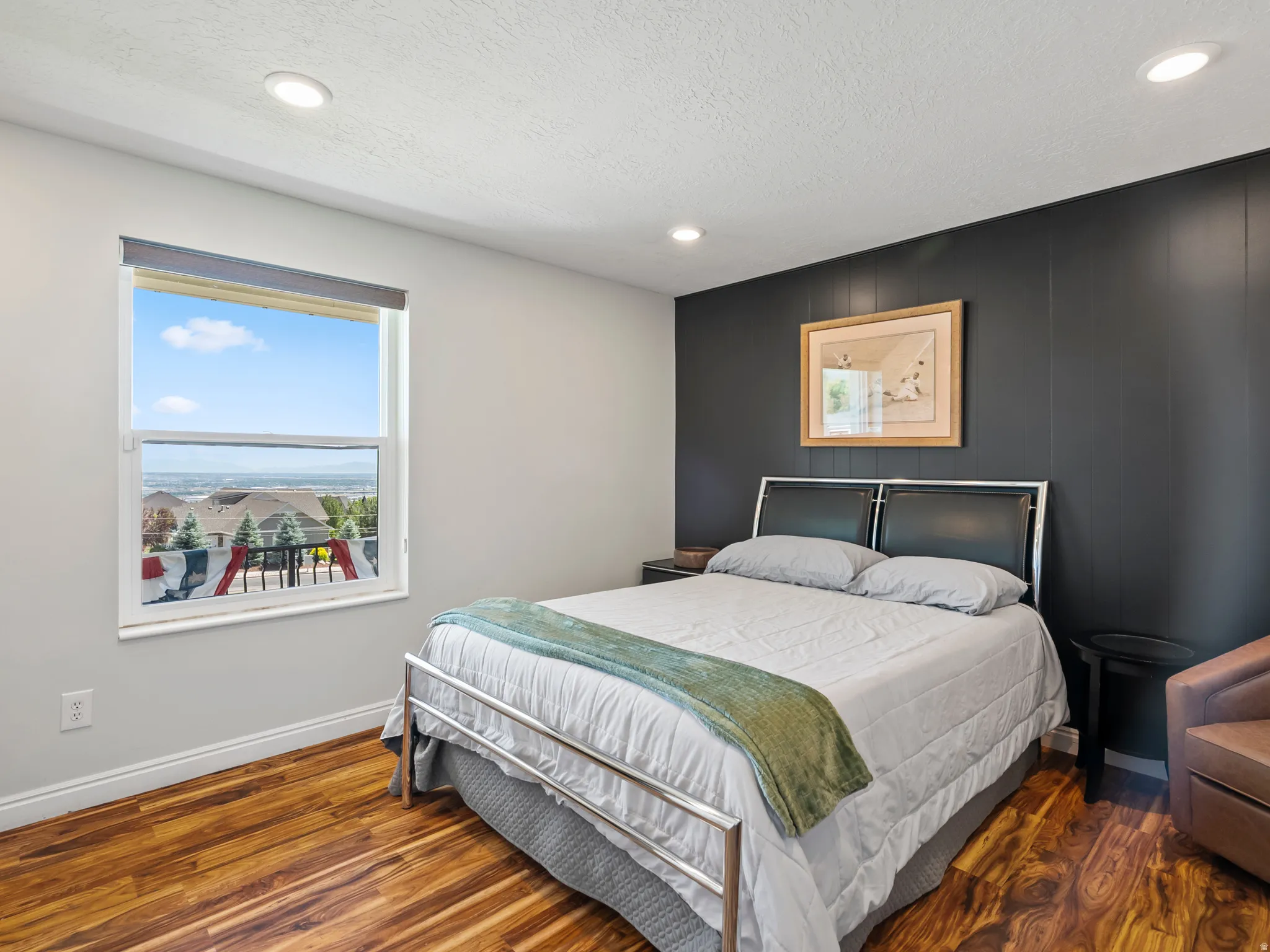 Bedroom featuring wood-finish flooring, recessed lighting, and a window with a distant landscape