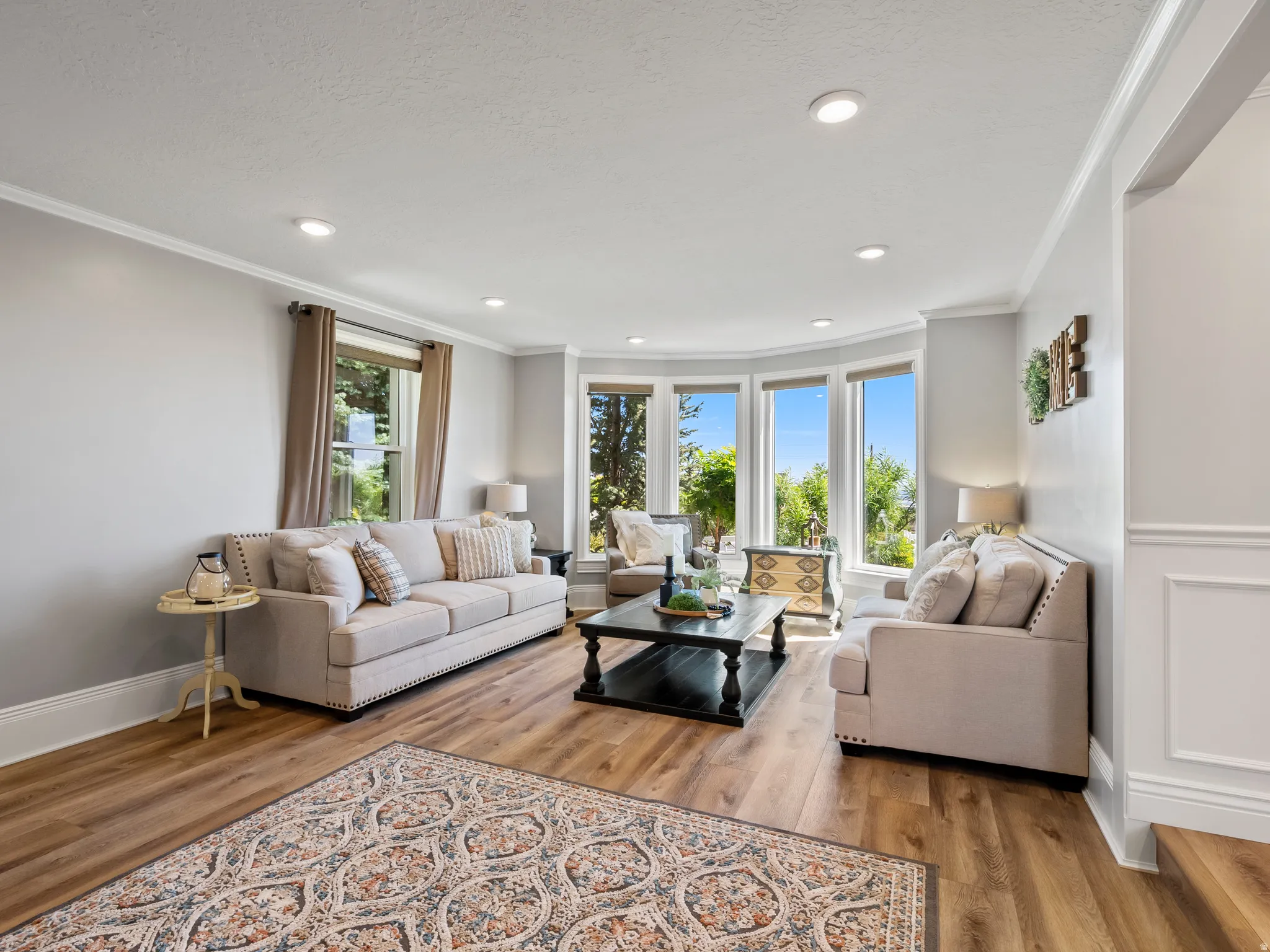 Living area featuring wood-finish flooring, recessed lighting, crown molding, and a bay window