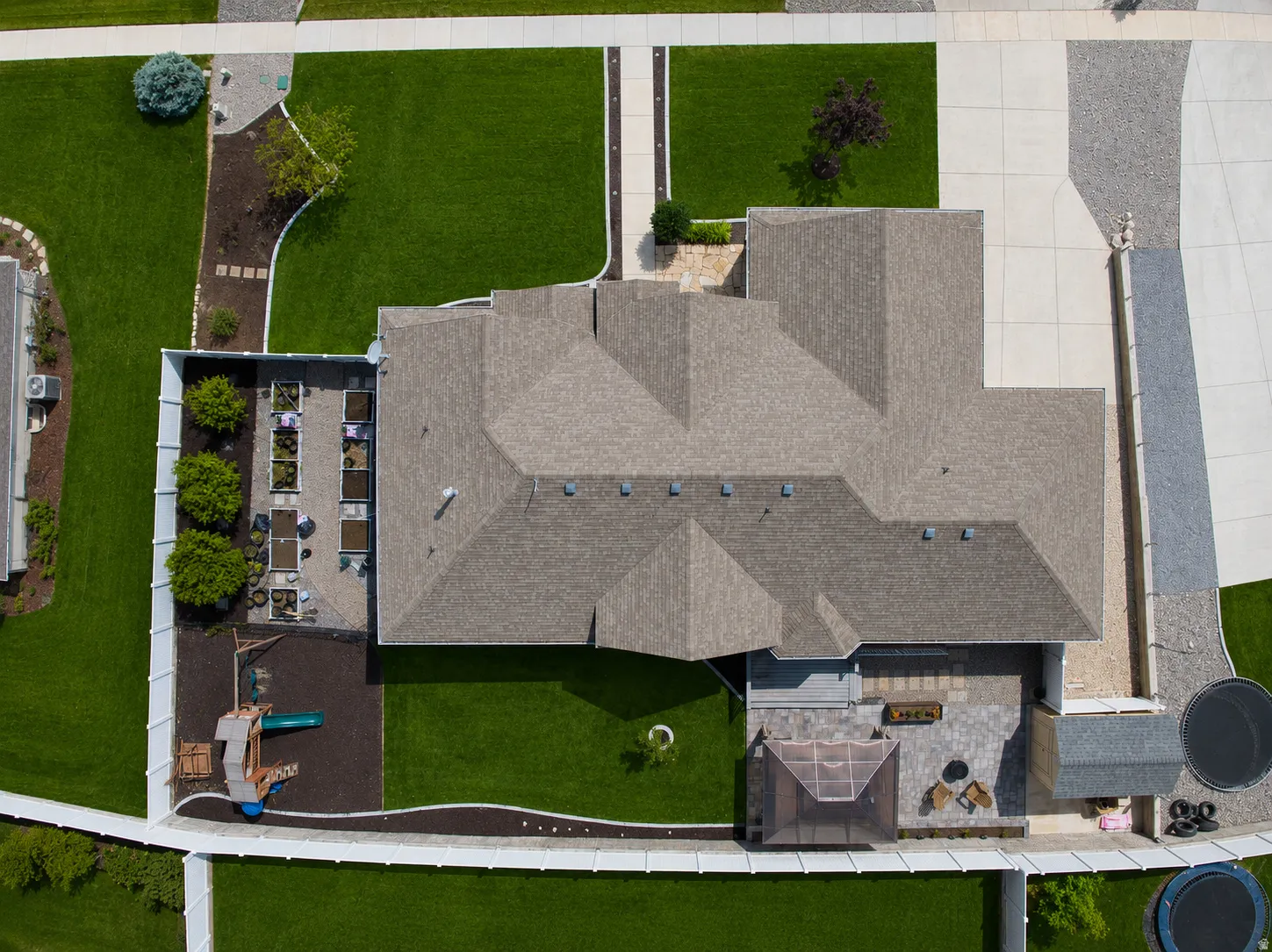 Residential property featuring a multi-gabled roofline, expansive paved driveway, and established landscaping