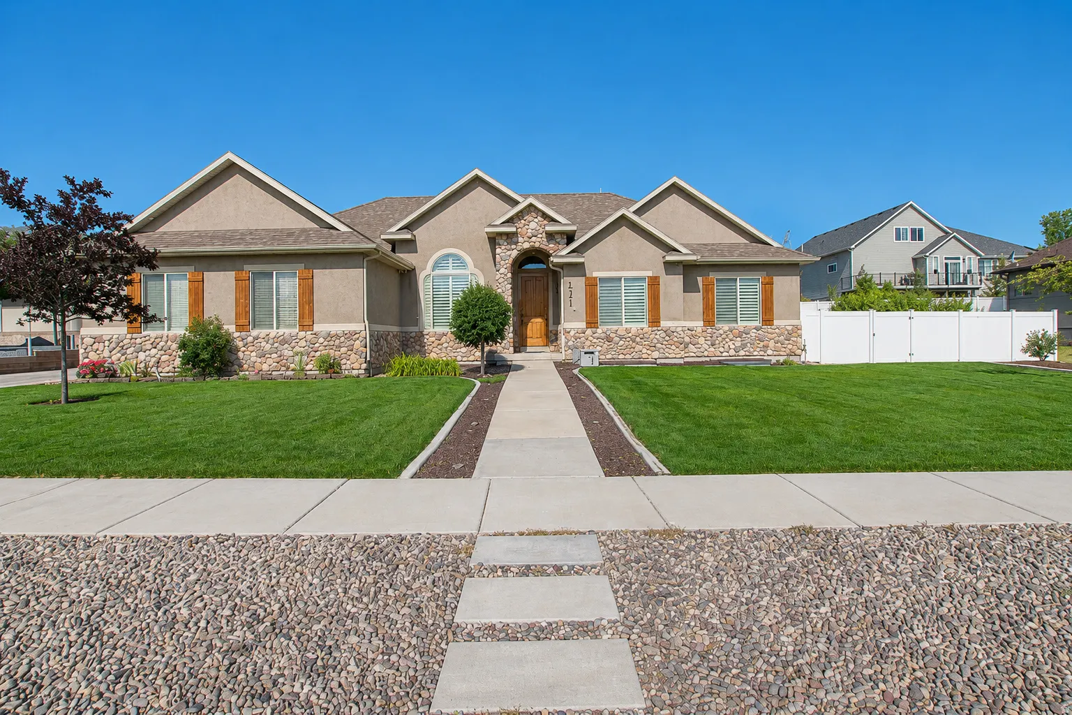 Stucco and stone exterior featuring a prominent arched entryway, multiple gables, and decorative wood shutters
