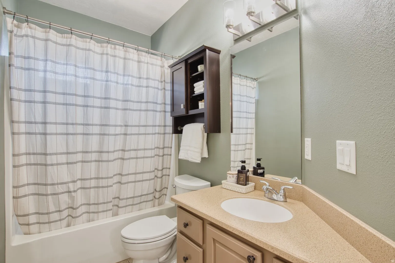 Bathroom featuring a tub/shower combination, a vanity with an integrated sink, a large wall-mounted mirror, a built-in medicine cabinet, and a toilet
