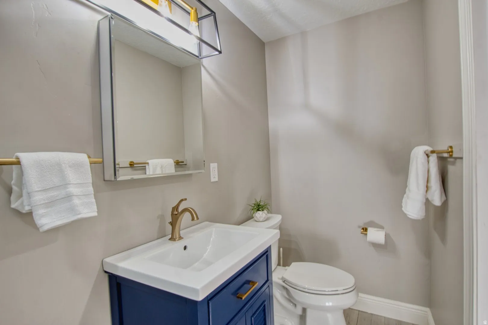 Modern bathroom vanity in a deep blue finish with gold-toned hardware, an integrated white sink, and a matching gold-toned faucet