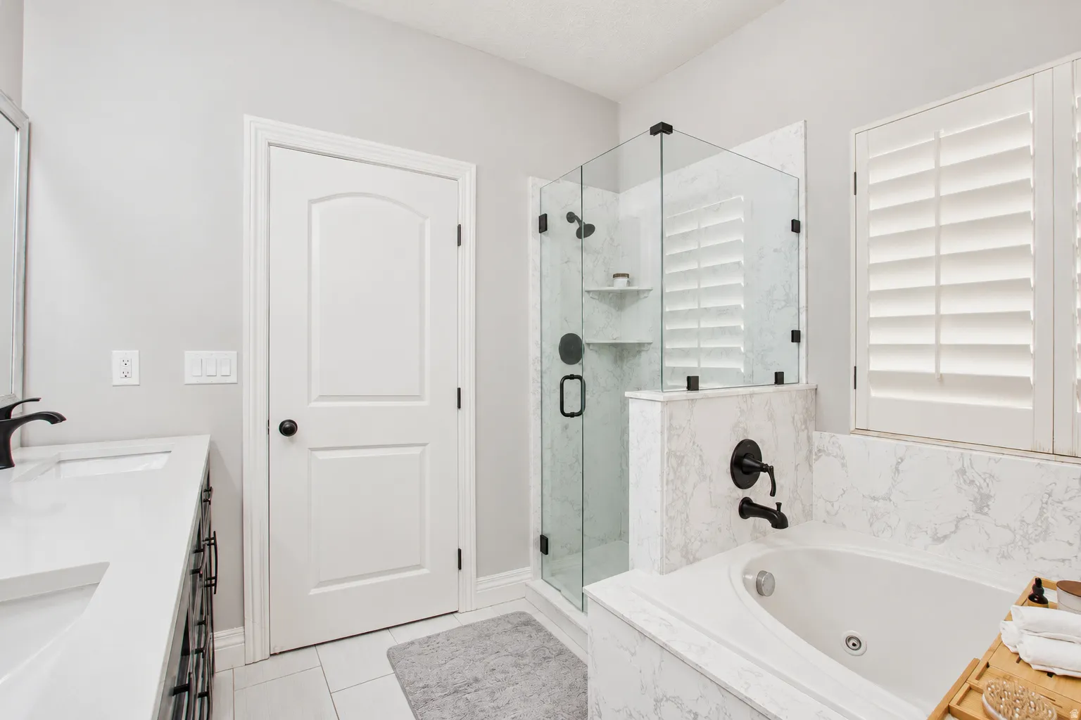 Bathroom featuring a walk-in glass shower, a soaking tub, and a dual vanity with undermount sinks