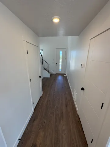 Bright hallway featuring dark wood-finish flooring, white painted walls, and recessed ceiling lighting