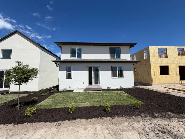 Two-story exterior with stucco finish, multiple windows, and a sliding glass door leading to a newly sodded lawn area