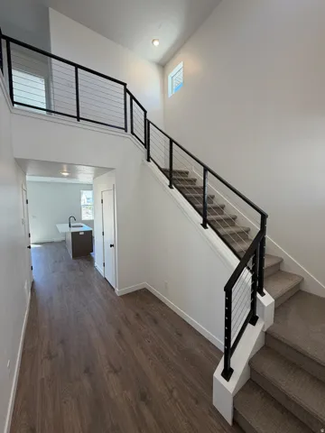 Wood-finish flooring, contemporary cable railing, recessed lighting, and carpeted stairs