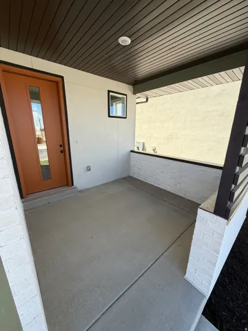 Inviting covered porch with concrete flooring and white brick accents