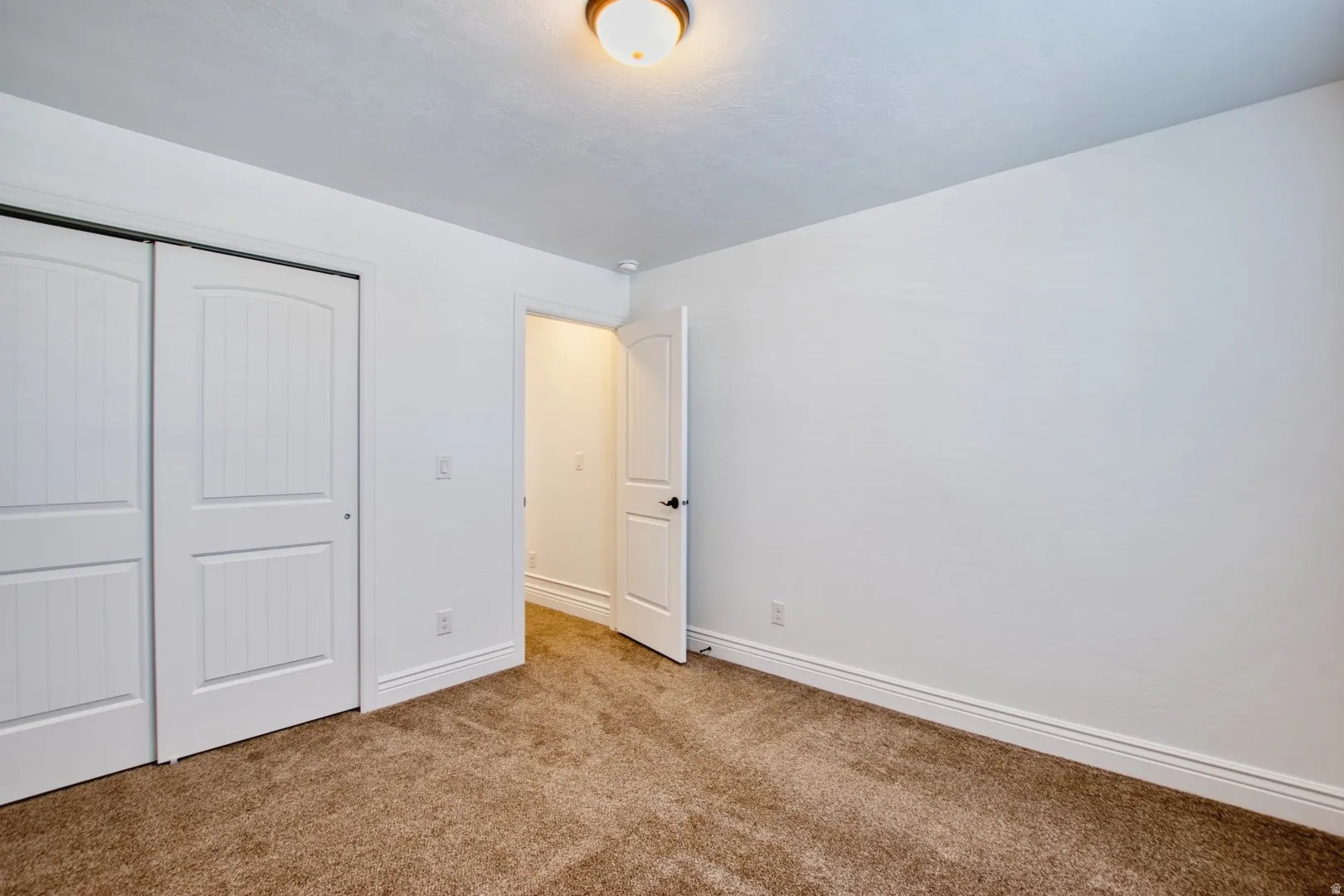 Neutral-toned wall-to-wall carpeting complements the white walls and trim