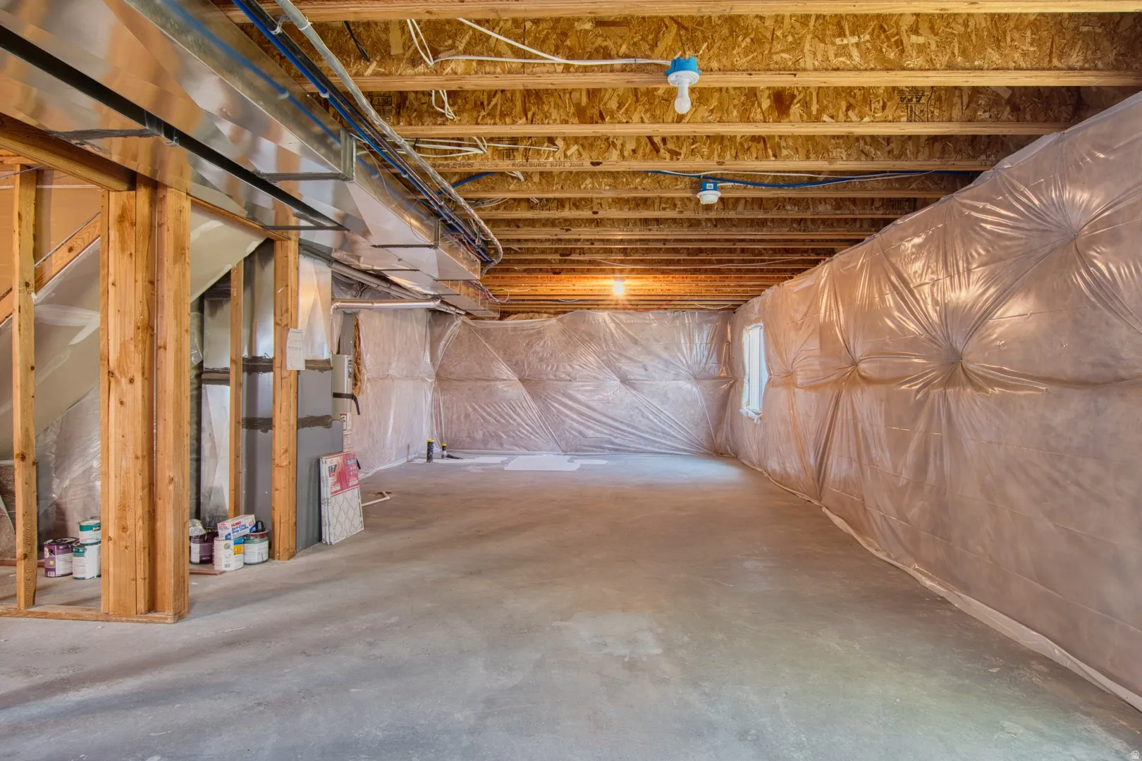 Unfinished basement featuring exposed wood framing, concrete flooring, visible overhead ductwork, and insulated walls