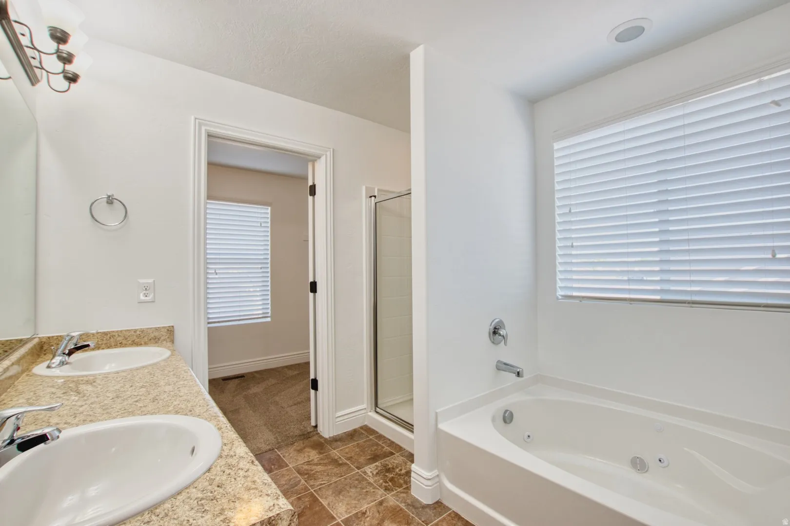 Primary Bathroom with double vanity with integrated sinks and stone-finish countertop