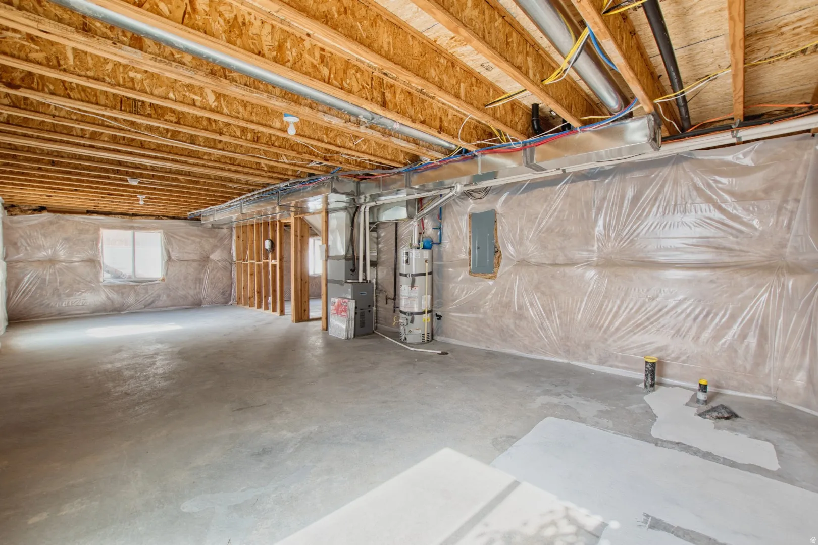 Unfinished lower level featuring exposed wood joists and concrete flooring