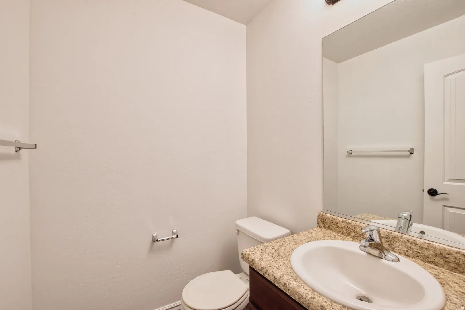 Bathroom featuring a built-in vanity with a speckled countertop, an undermount sink, and a large wall-mounted mirror