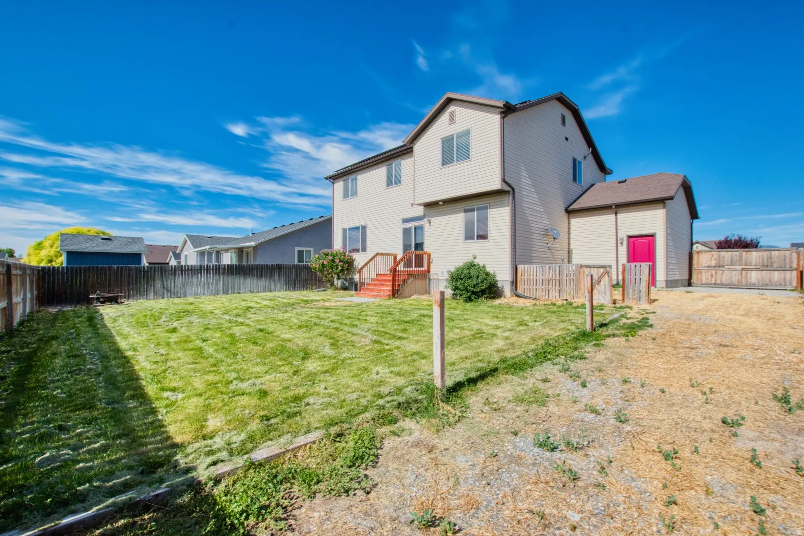 Expansive backyard with a manicured lawn, multi-level deck, and full perimeter fencing