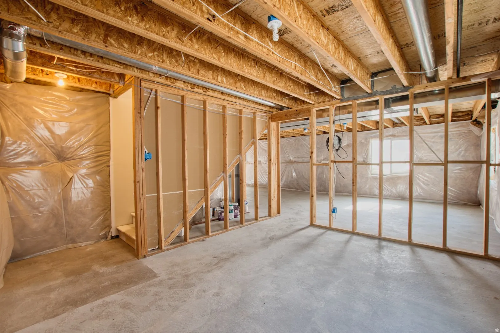 Unfinished basement with concrete flooring, exposed wood joists, and framed partition walls