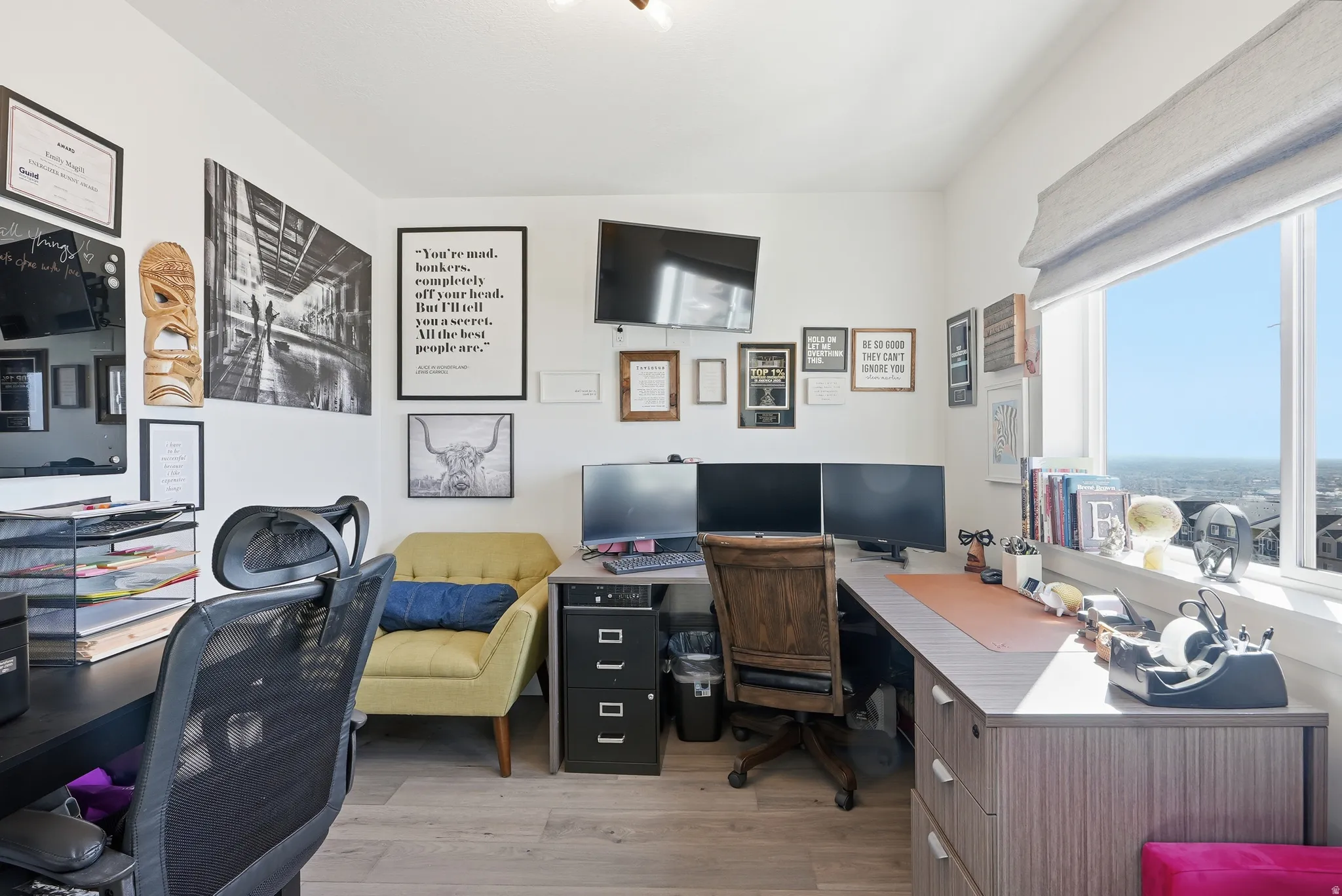 Bright room with wood-finish flooring and multiple windows featuring roller shades