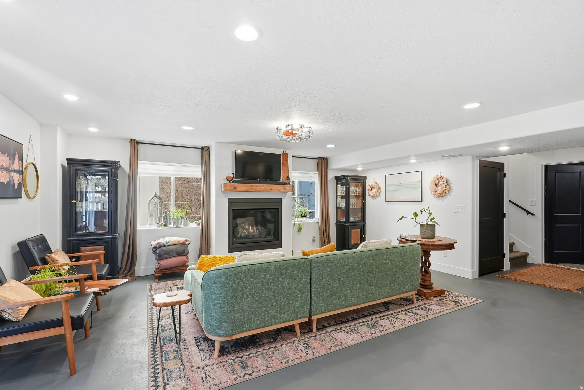 Spacious living area featuring recessed lighting, a fireplace with a wood mantel, and multiple windows