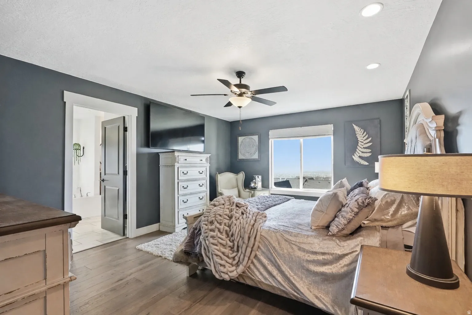 Spacious room featuring wood-finish flooring, a ceiling fan with integrated lighting, and recessed ceiling lights