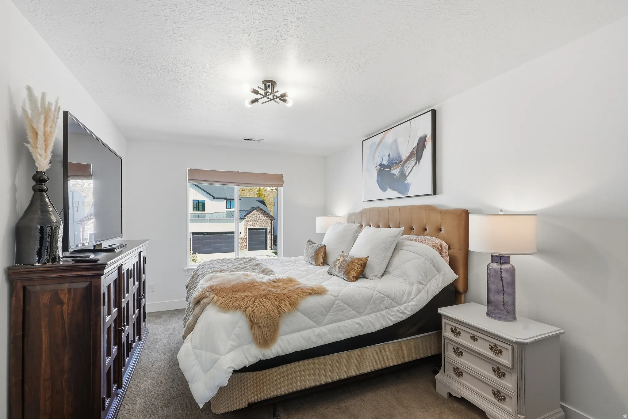 Spacious bedroom featuring light neutral wall paint, a modern ceiling light fixture, a window with a brown blind, and carpeted flooring