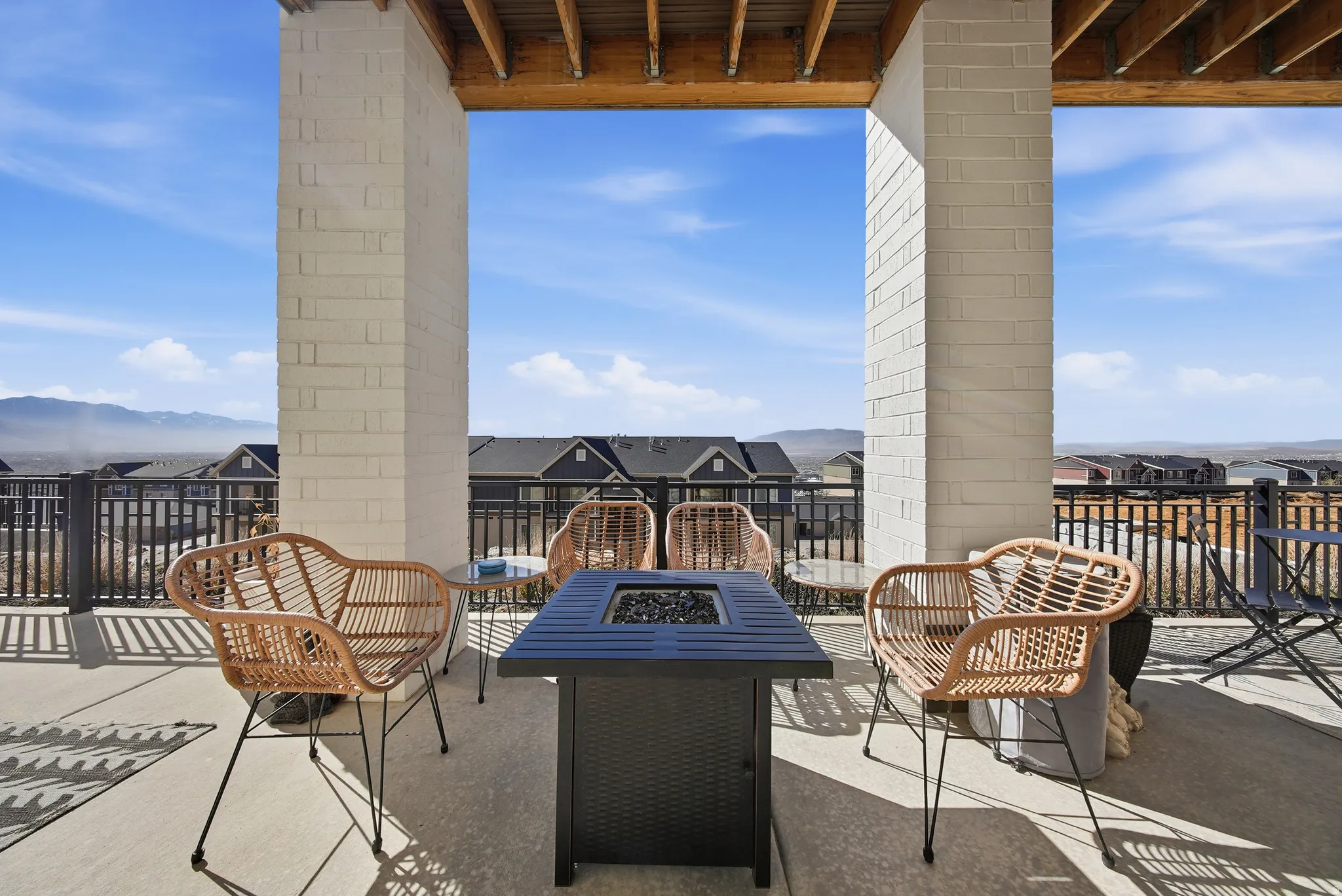 Spacious outdoor patio featuring concrete flooring, a fire pit, and durable black metal railings