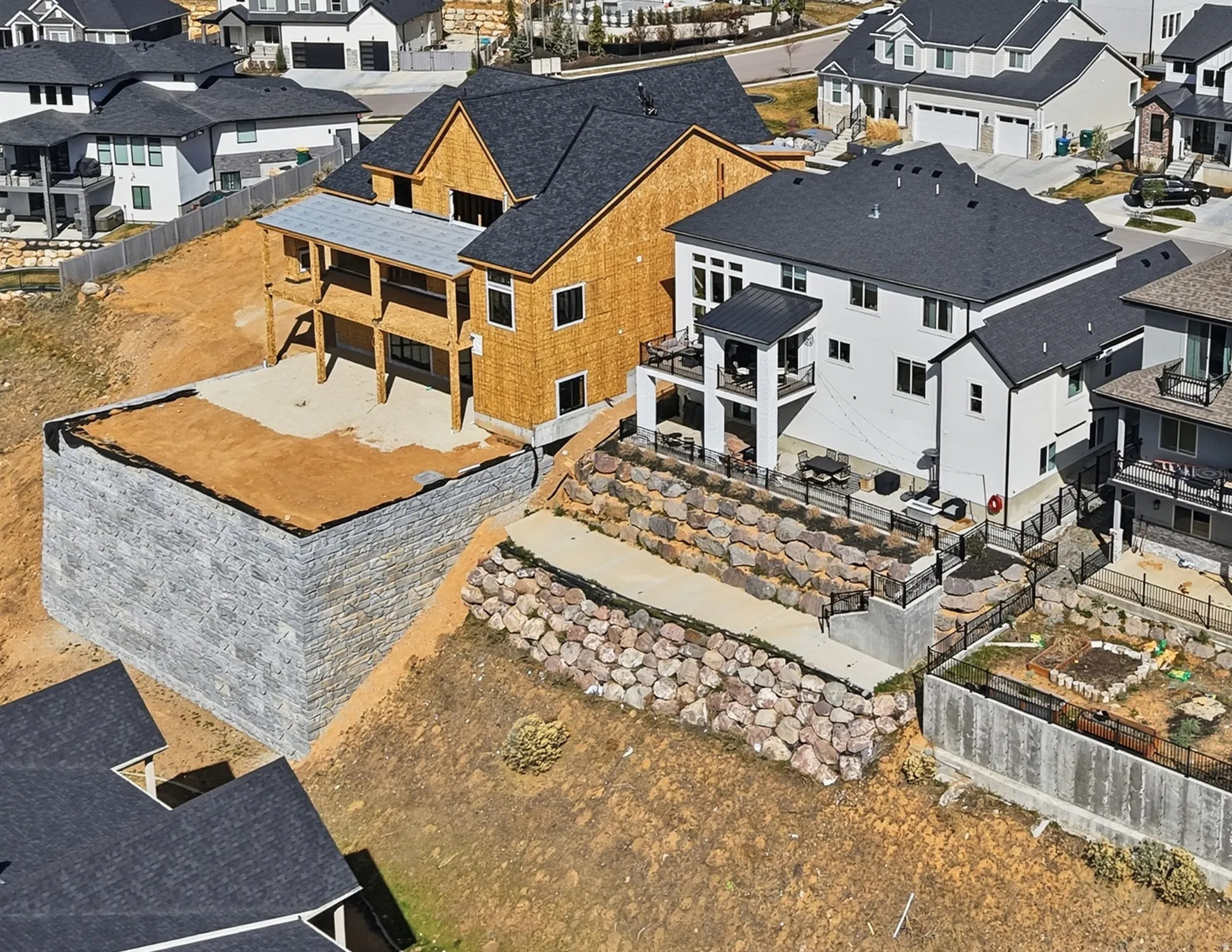 Newly constructed residence featuring a multi-level deck and stone retaining walls