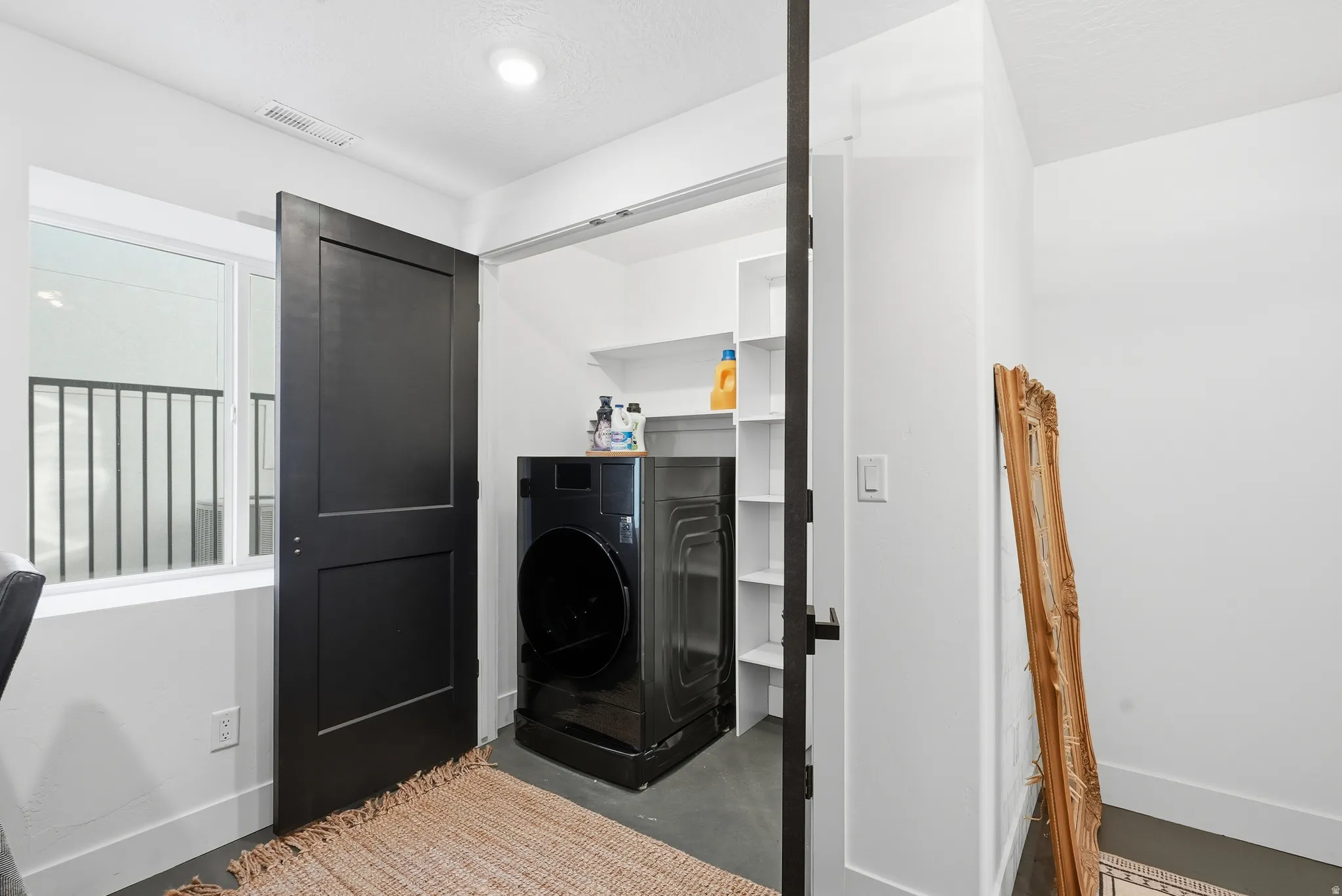 Dedicated laundry closet featuring a front-load washer and dryer, accompanied by built-in shelving for organization