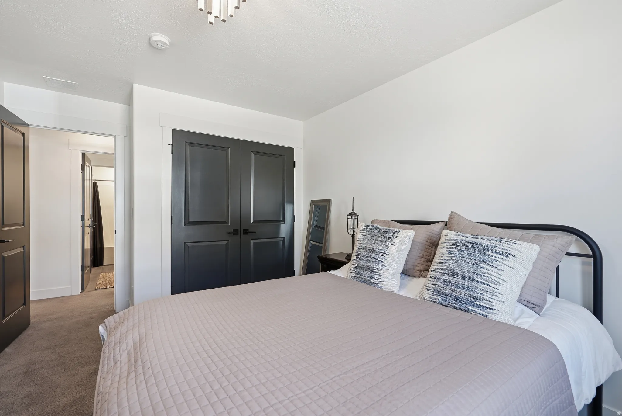 Bedroom featuring modern dark paneled doors, neutral carpeting, and white walls